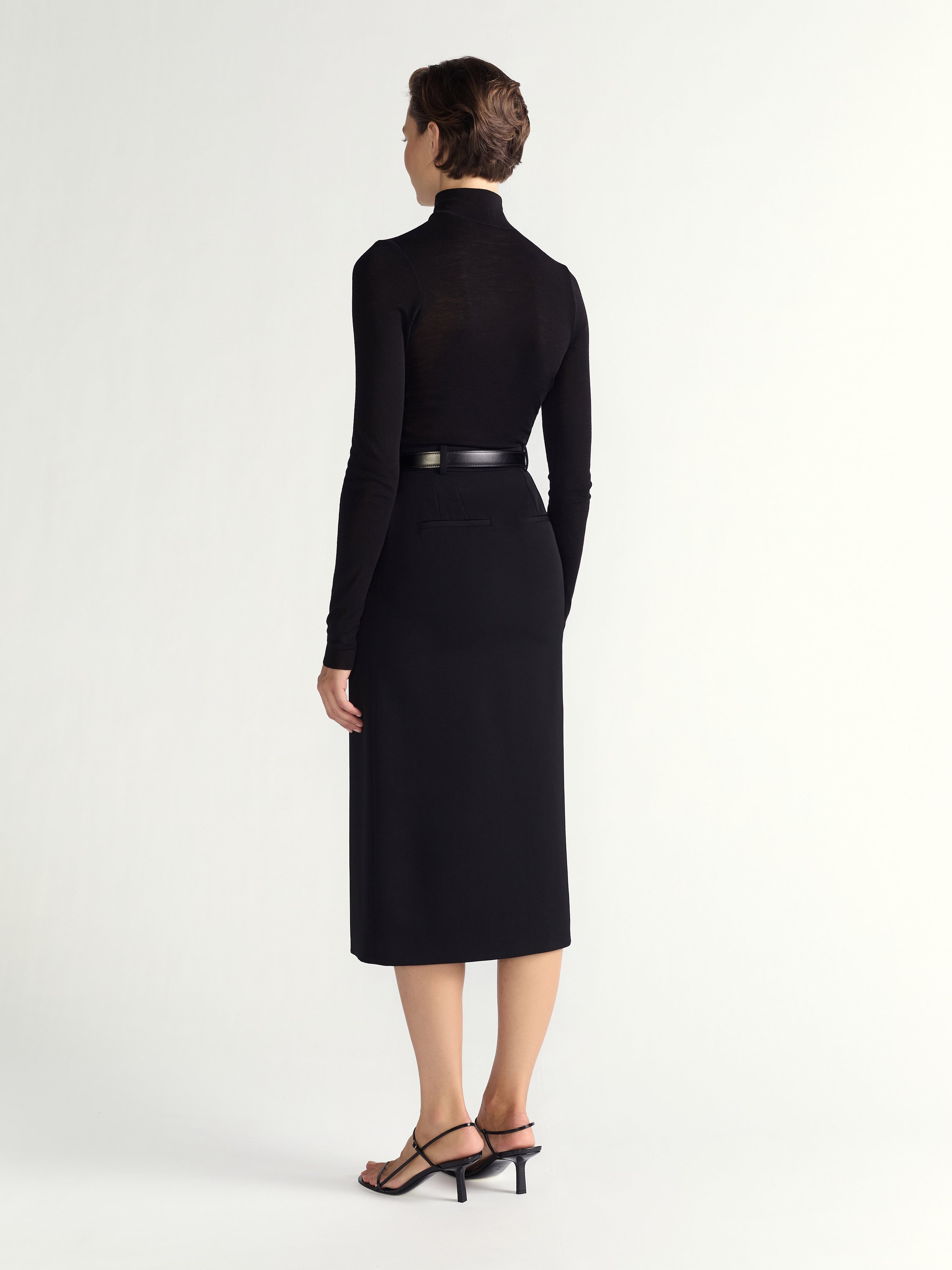 Woman wearing a black dress with a belt on a white background