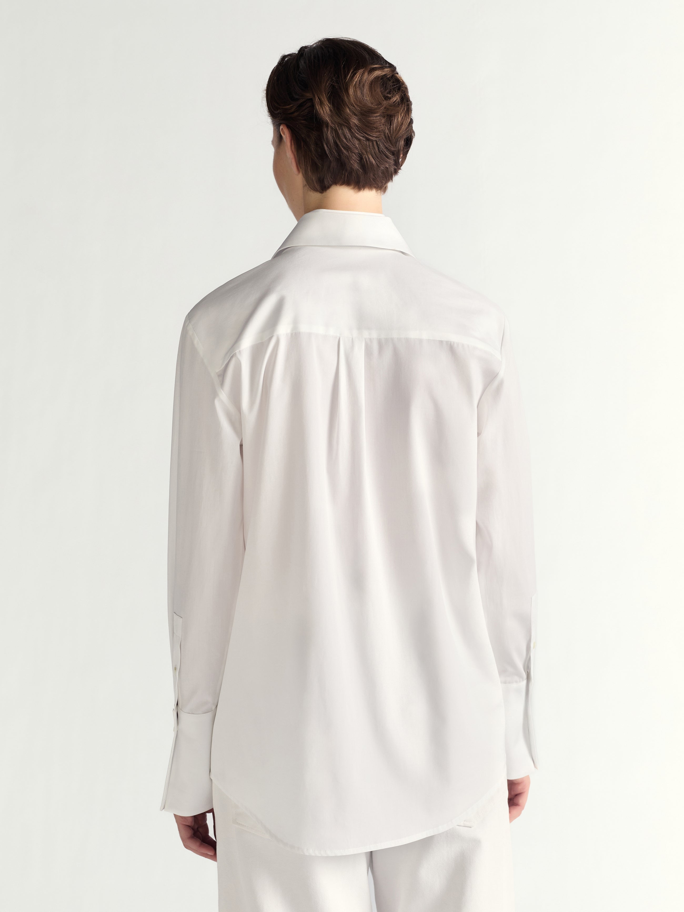 Person wearing a white dress shirt and pants on a plain background