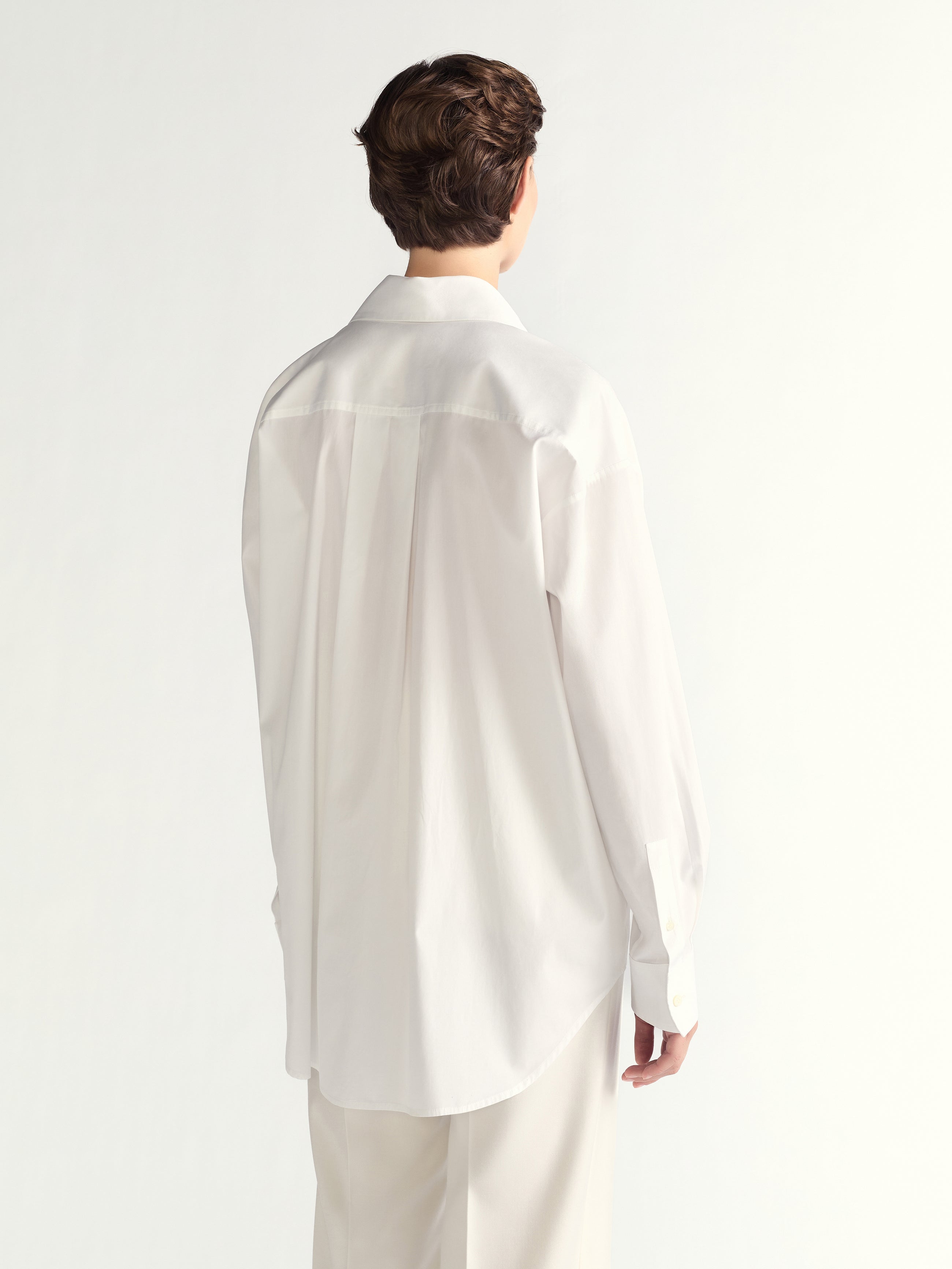 Person wearing a white shirt and pants on a light gray background