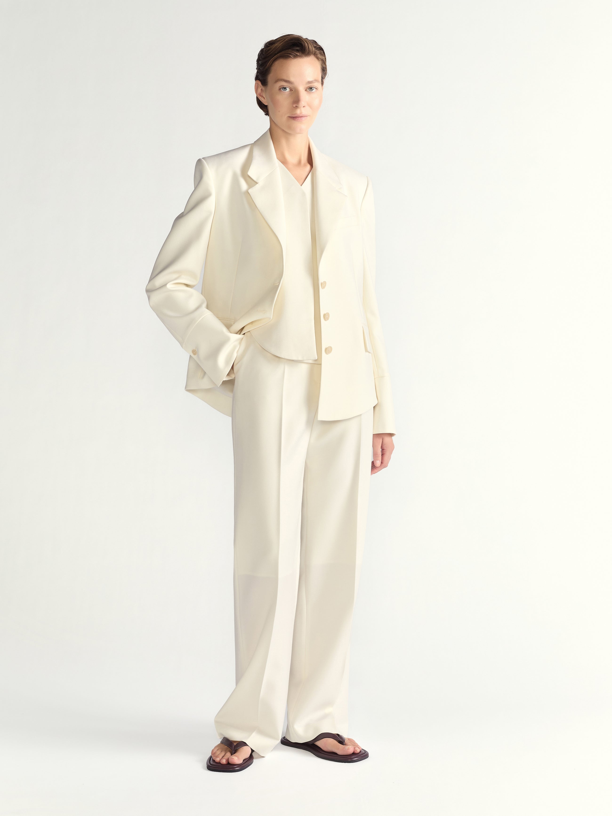 Woman wearing a cream-colored suit on a white background