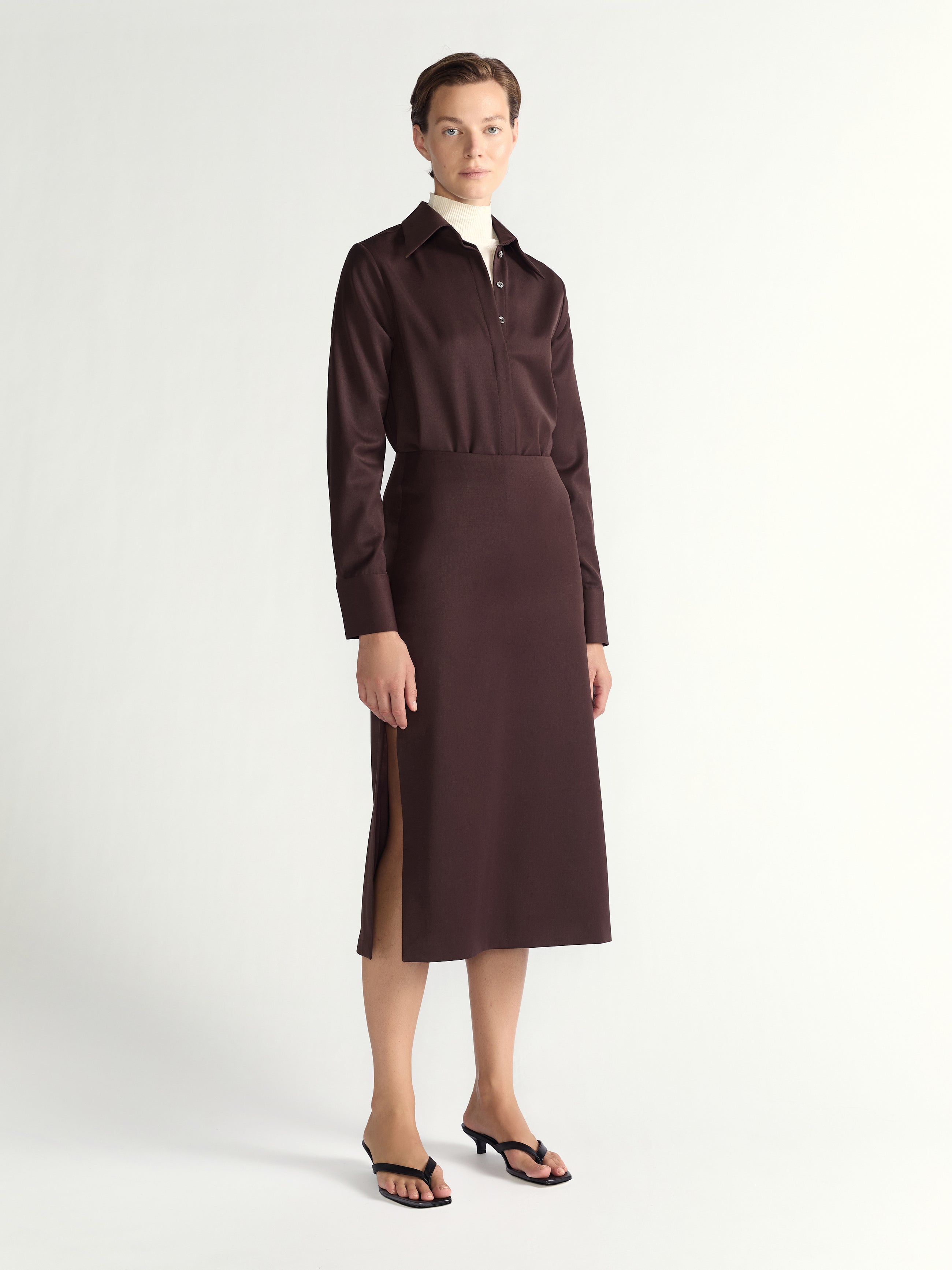 Woman wearing a brown skirt with a brown shirt on a light gray background