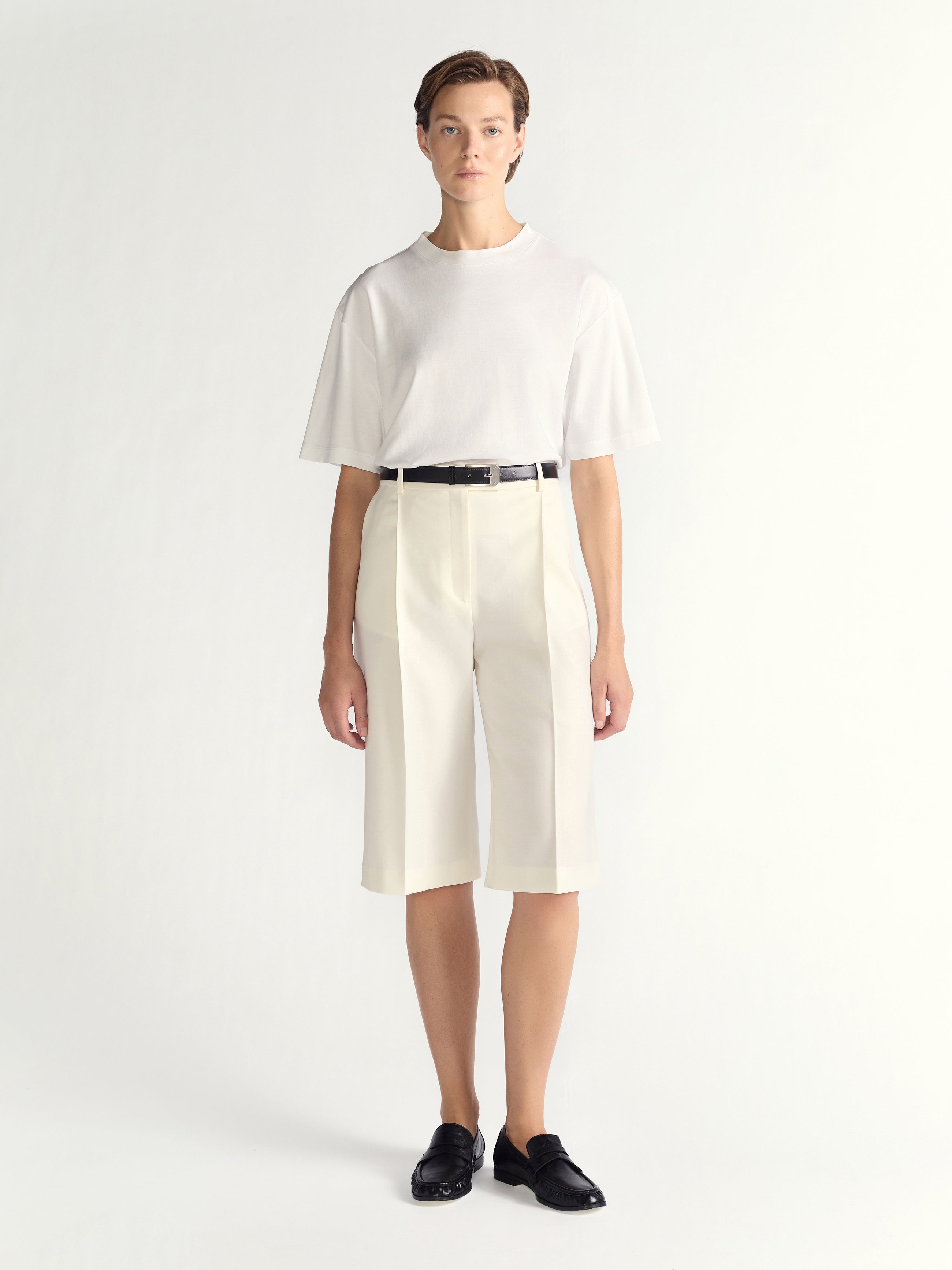 Person wearing a white outfit with a black belt on a white background