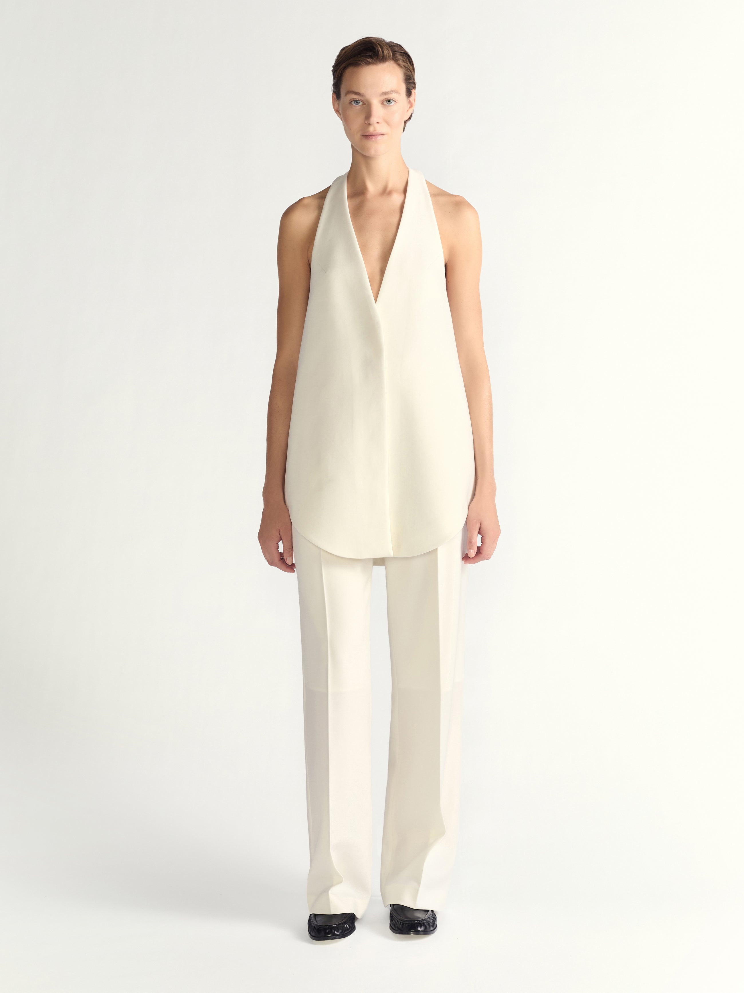 Woman wearing a white sleeveless top and pants on a white background