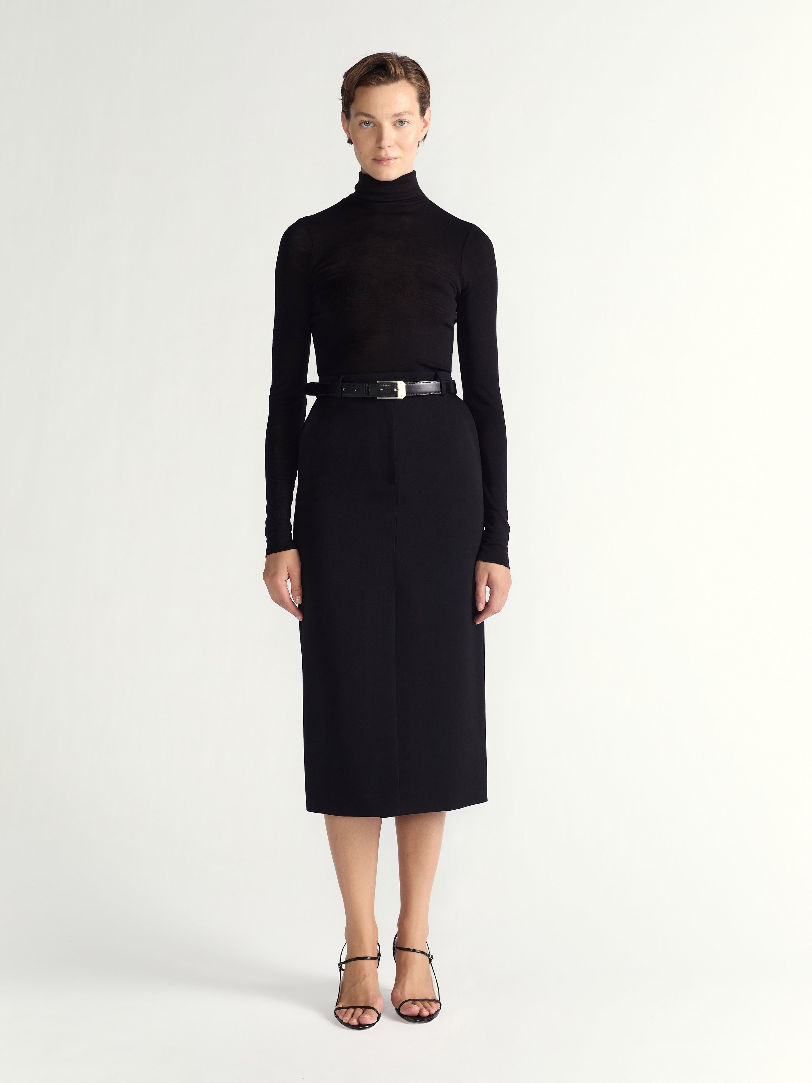 Woman wearing a black turtleneck and black skirt on a white background