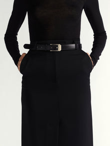 Person wearing a black outfit with a belt on a white background