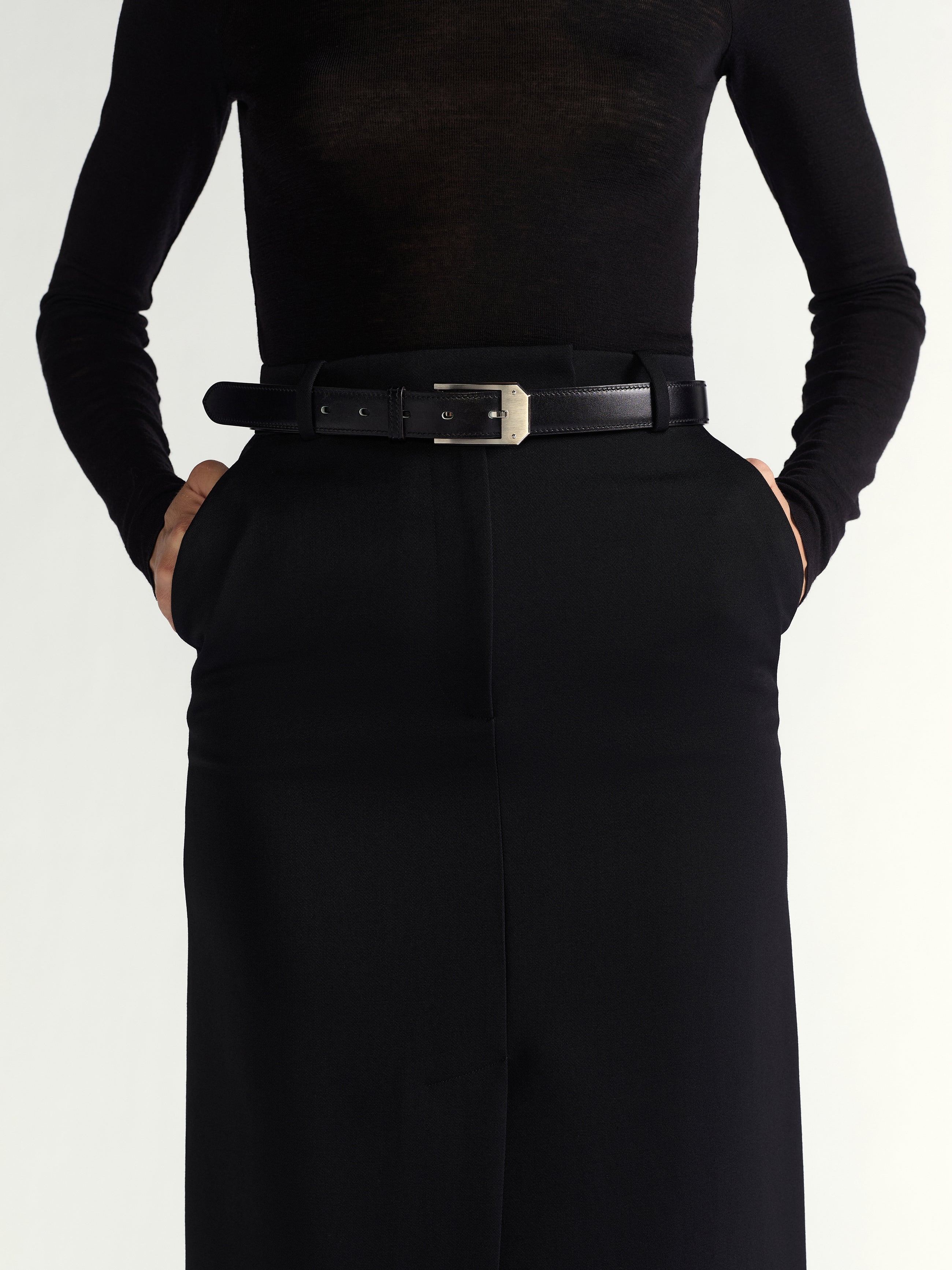 Person wearing a black outfit with a belt on a white background