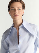 Person wearing a light blue striped shirt against a white background