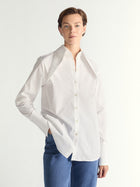 Person wearing a white blouse with a collar on a plain background