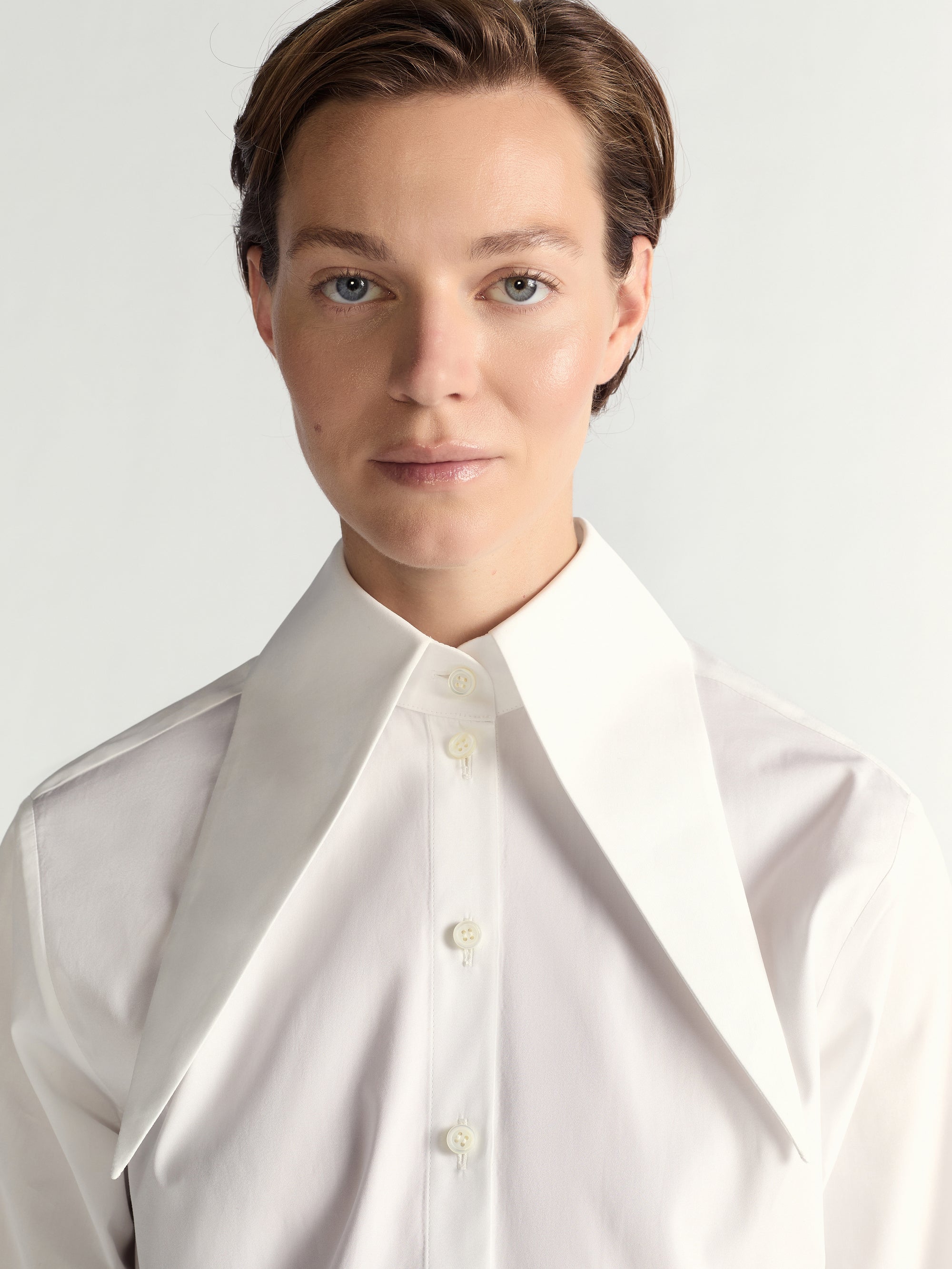 Person wearing a white shirt against a light gray background