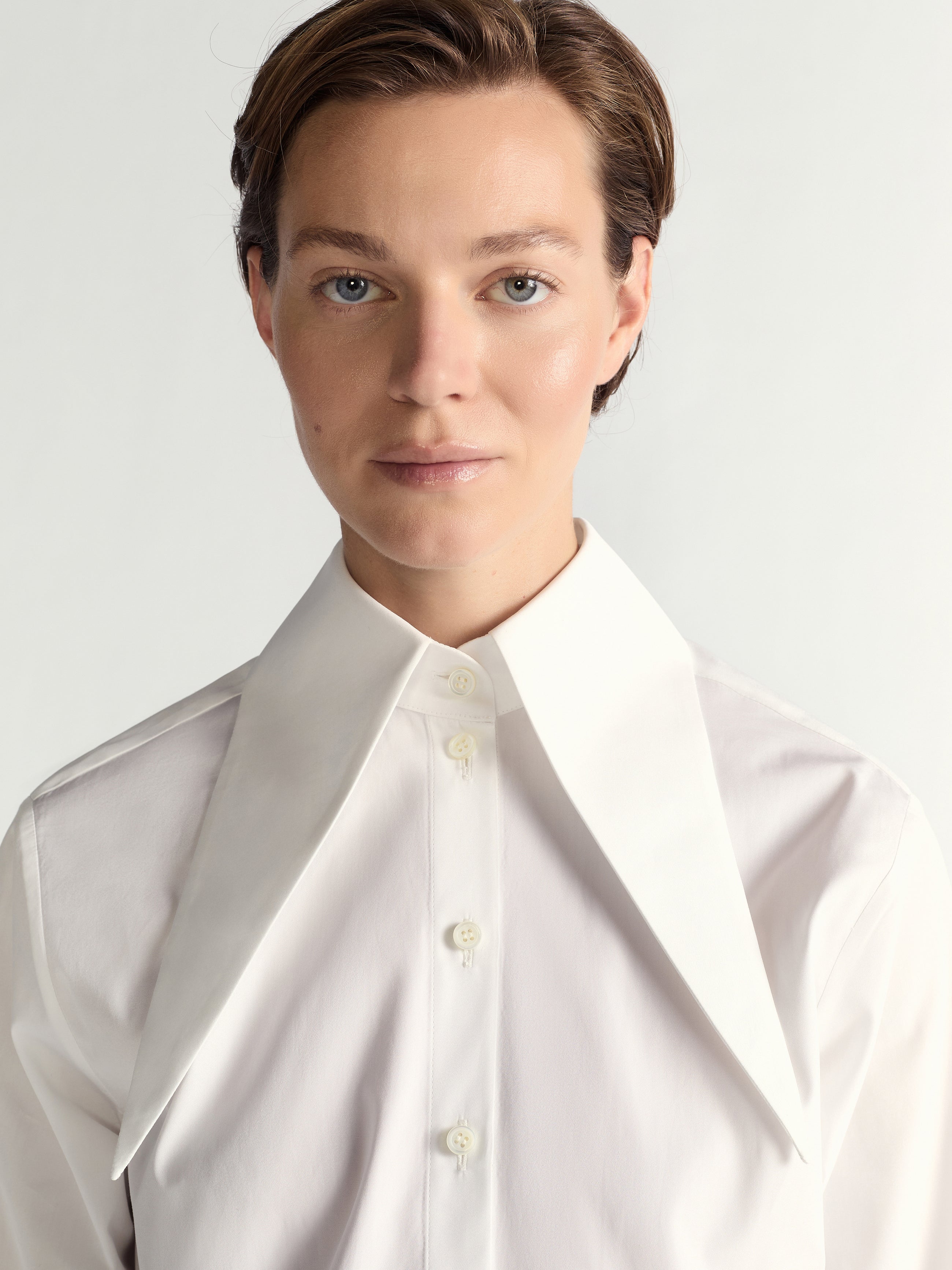 Person wearing a white shirt against a light gray background