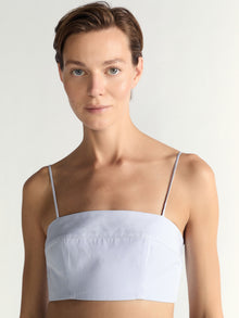 Woman wearing a light blue strapless top against a plain background