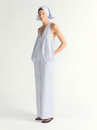 Woman wearing a blue halter dress with a headscarf on a plain background