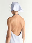 Person wearing a blue dress and a white headscarf on a light gray background