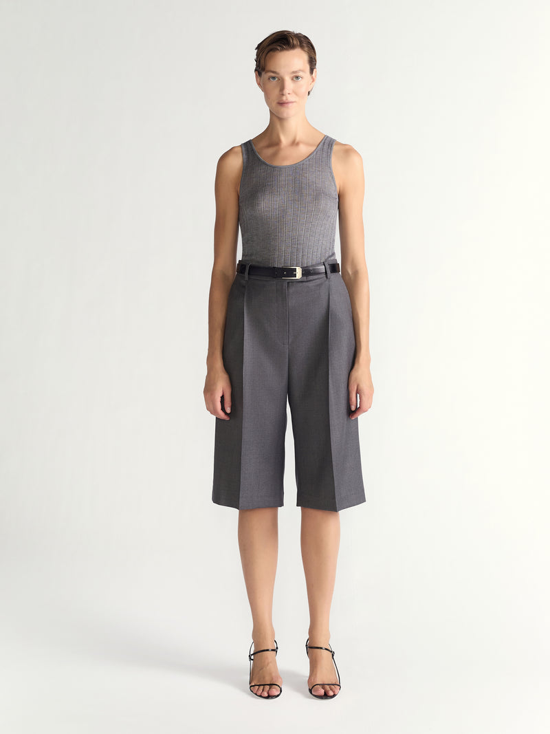 Woman wearing a sleeveless gray top and gray shorts on a white background