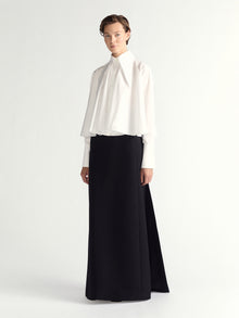 Woman wearing a white blouse and black skirt on a white background