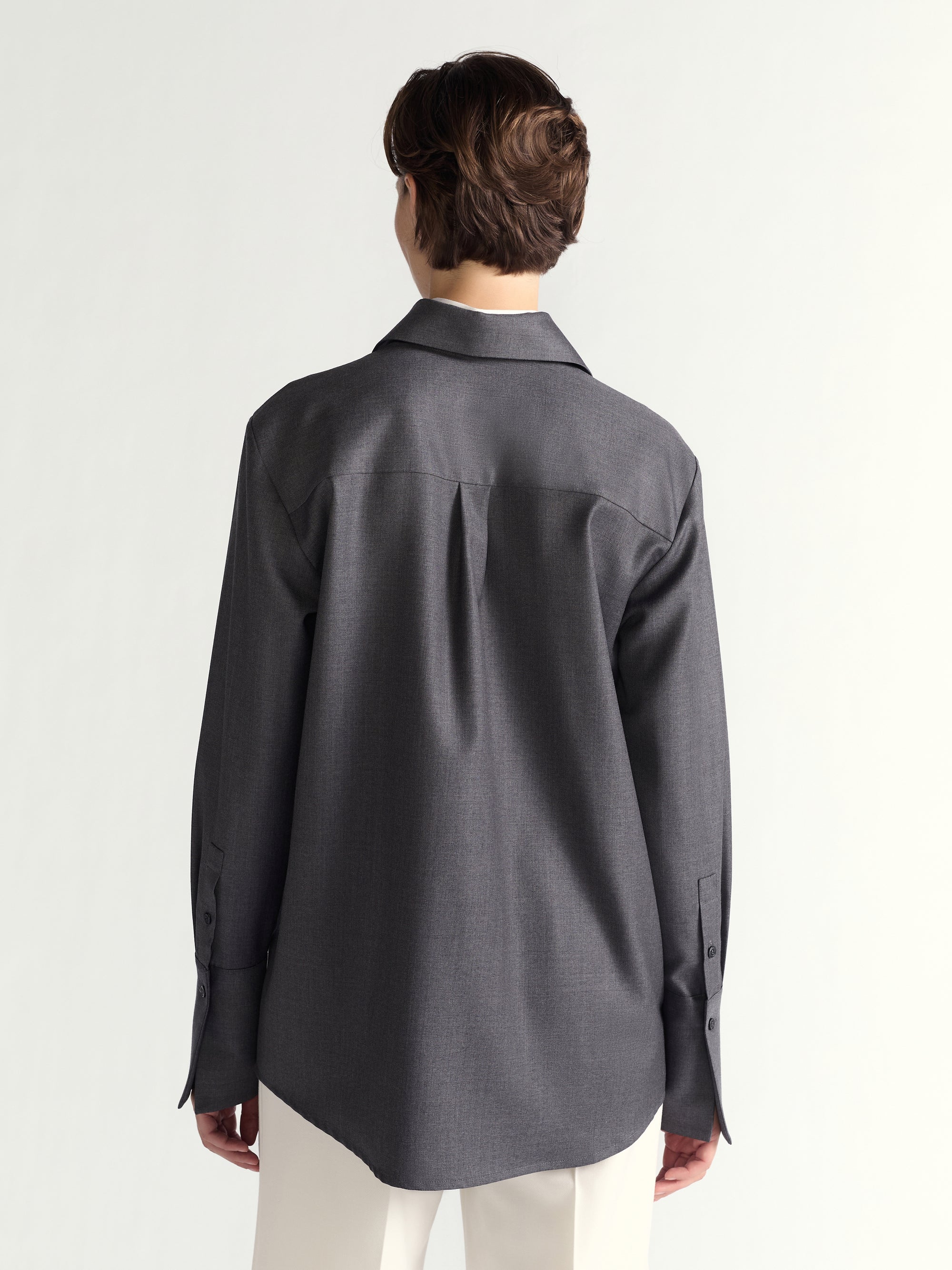 Person wearing a dark gray shirt from behind on a white background