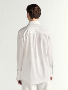 Person wearing a white dress shirt and pants on a plain background