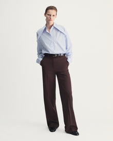 Person wearing a striped shirt and brown pants on a white background