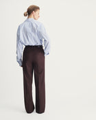 Person wearing a blue striped shirt and brown pants on a white background