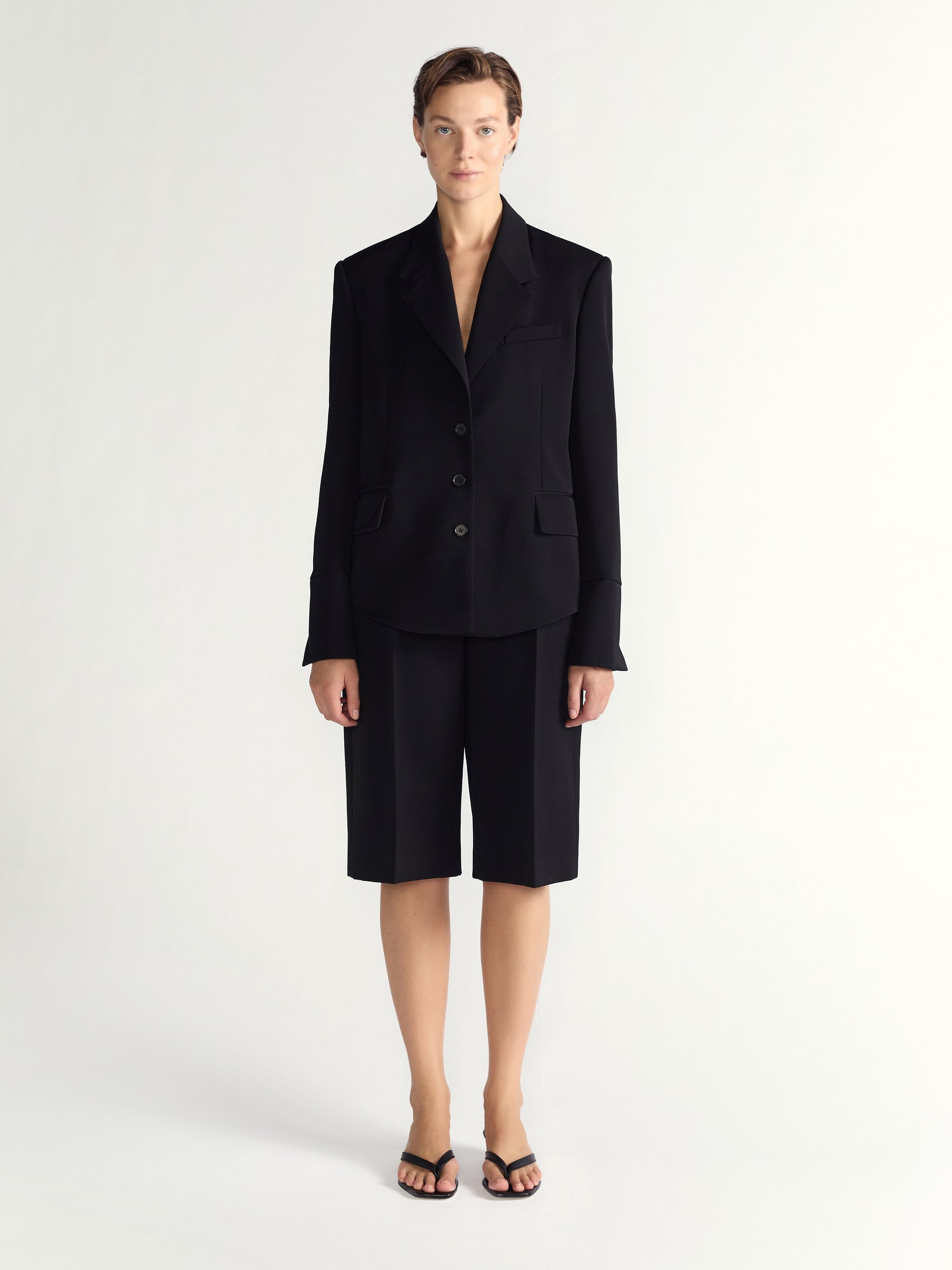 Person wearing a black suit with shorts on a white background