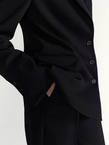Close-up of a black suit jacket with buttons on a light gray background
