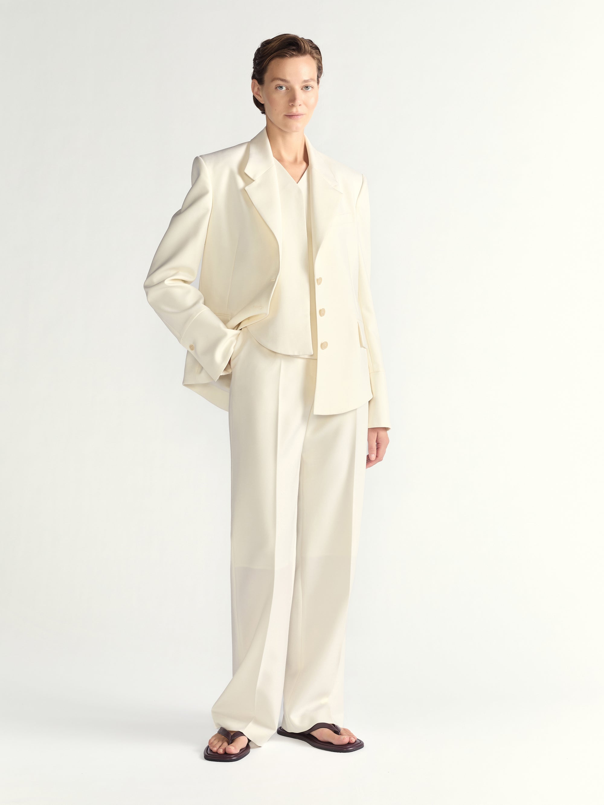 Woman wearing a cream-colored suit on a white background