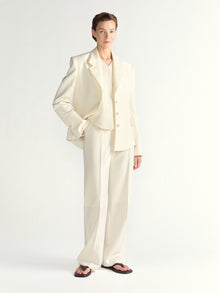 Woman wearing a cream-colored suit on a white background