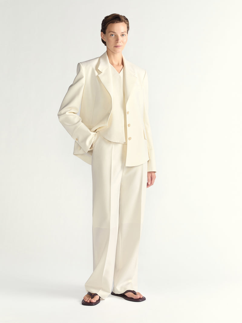 Woman wearing a cream-colored suit on a white background