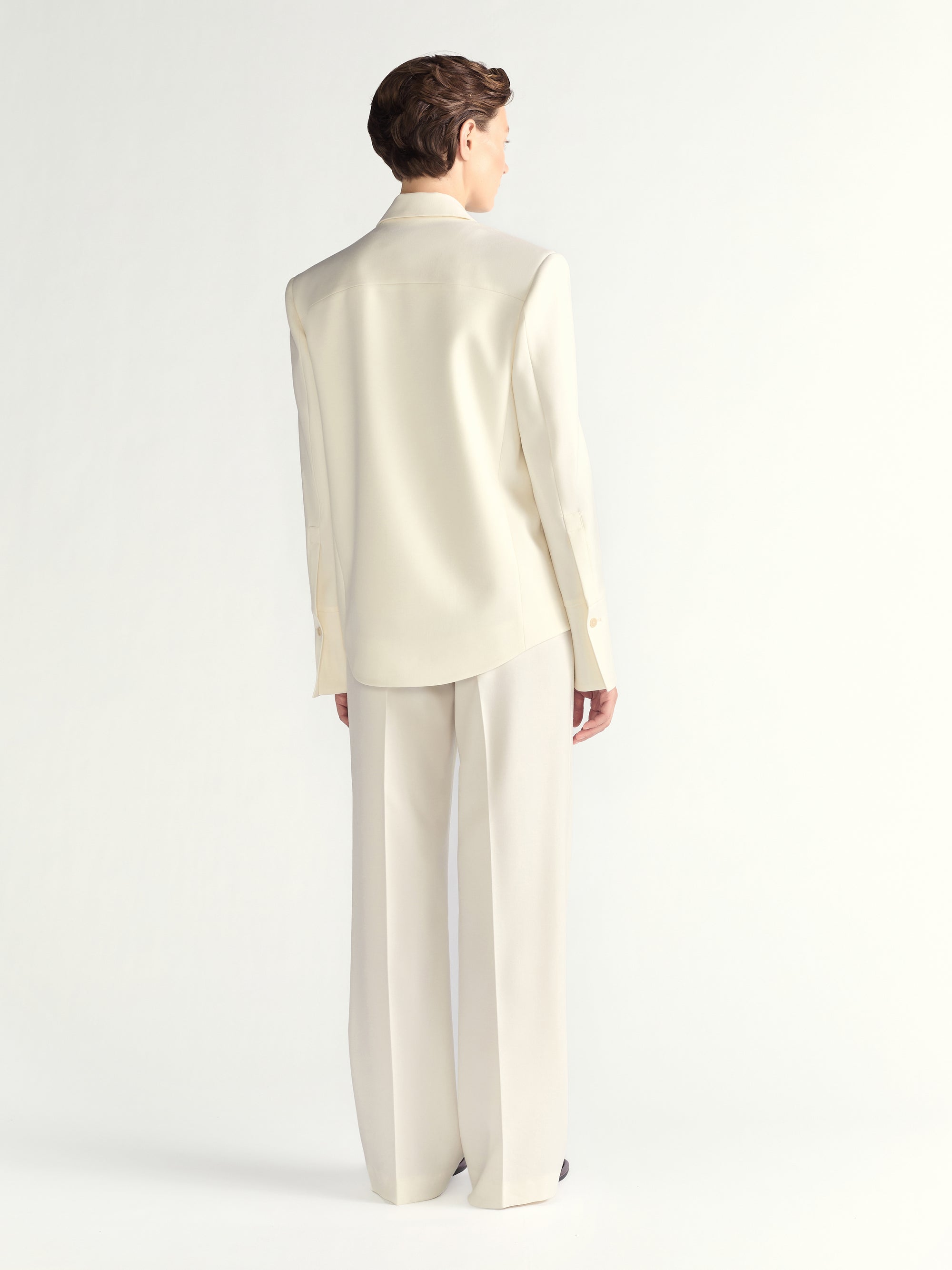 Person wearing a cream-colored suit on a white background