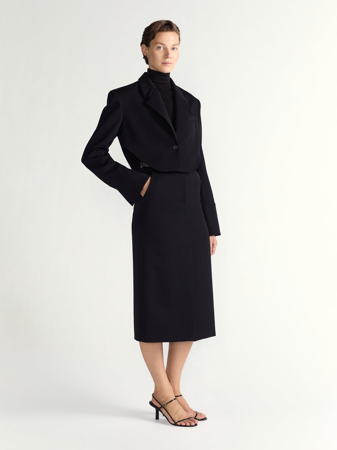 Woman wearing a black coat and skirt set on a white background