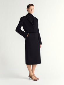 Woman wearing a black coat and skirt set on a white background