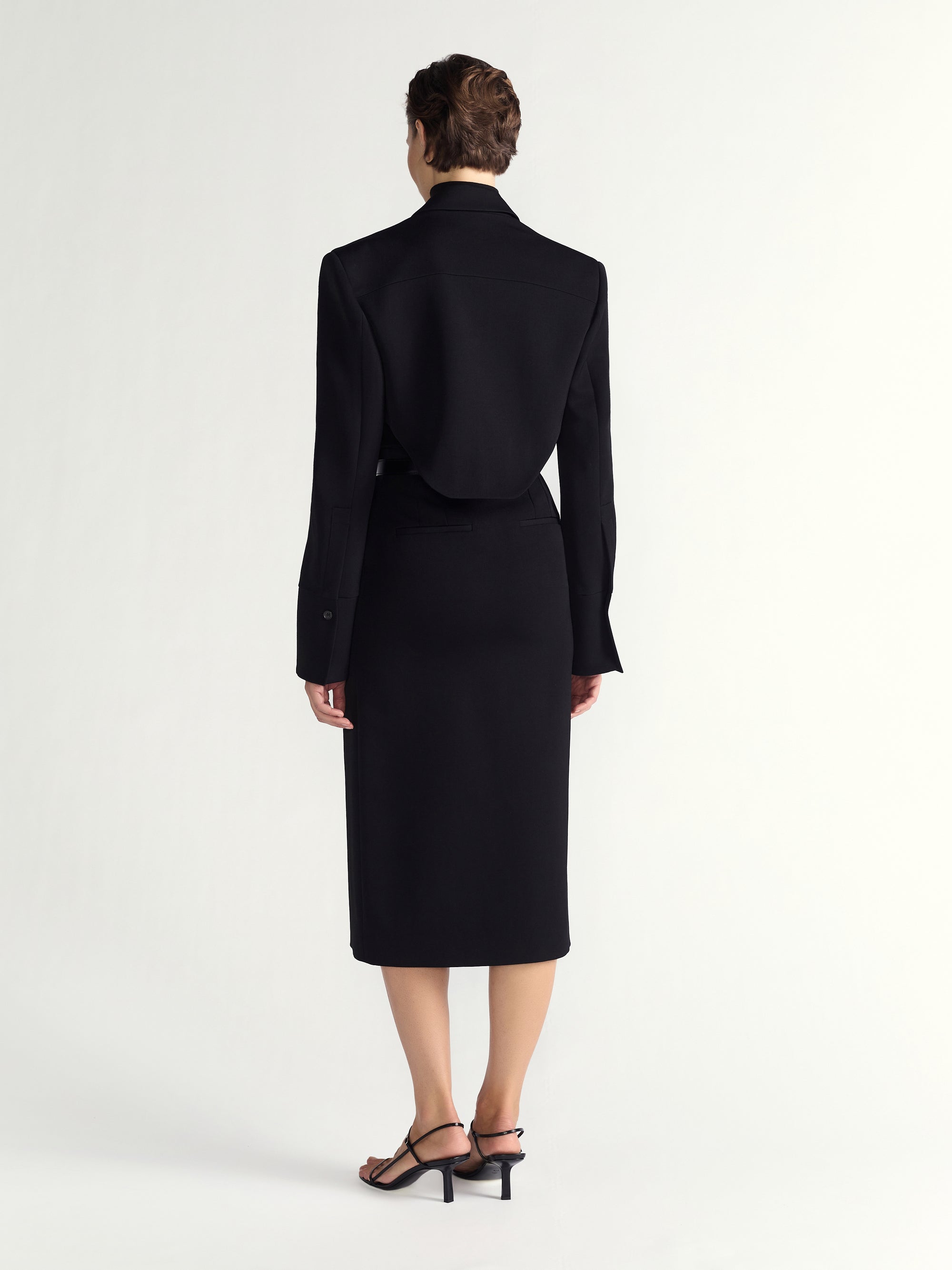 Person wearing a black suit on a white background