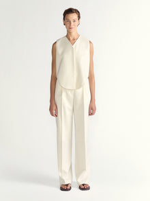 Woman wearing a white sleeveless top and pants on a white background