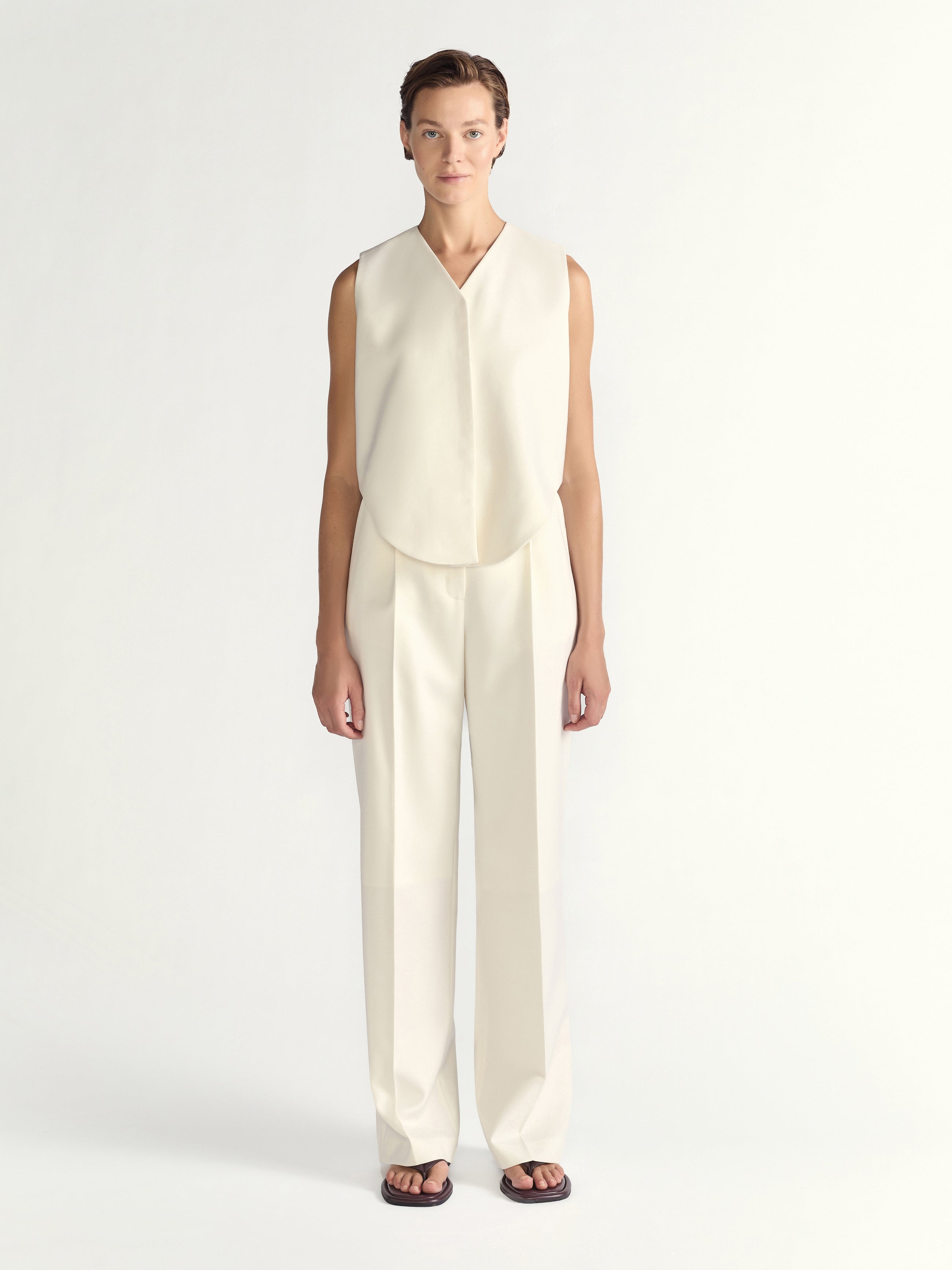 Woman wearing a white sleeveless top and pants on a white background