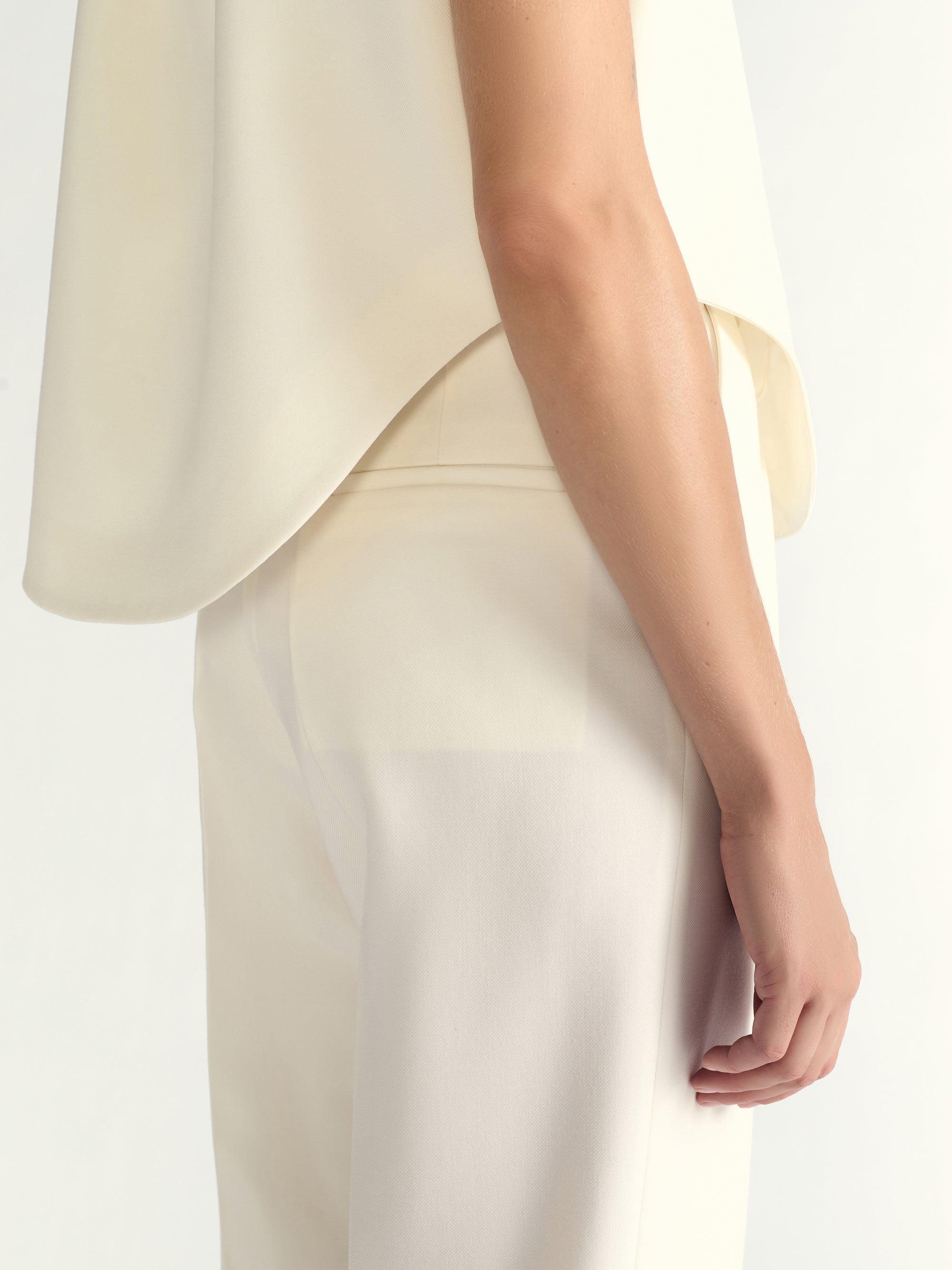 Close-up of a person wearing a light-colored outfit on a plain background