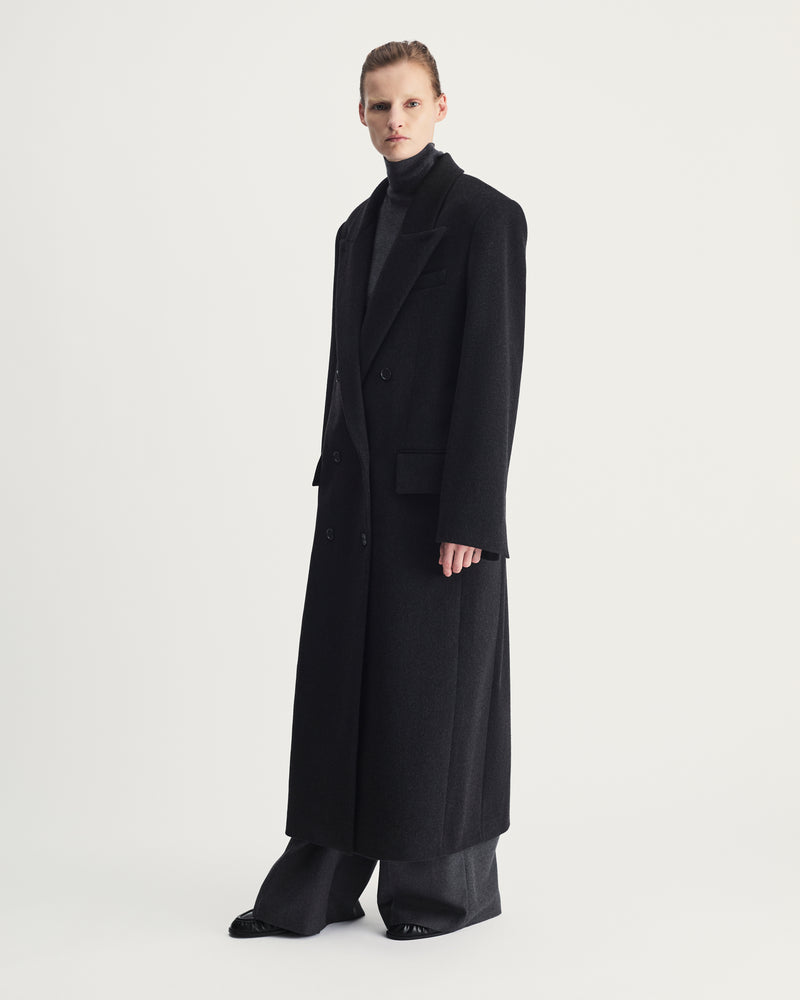 Person wearing a long grey coat on a white background