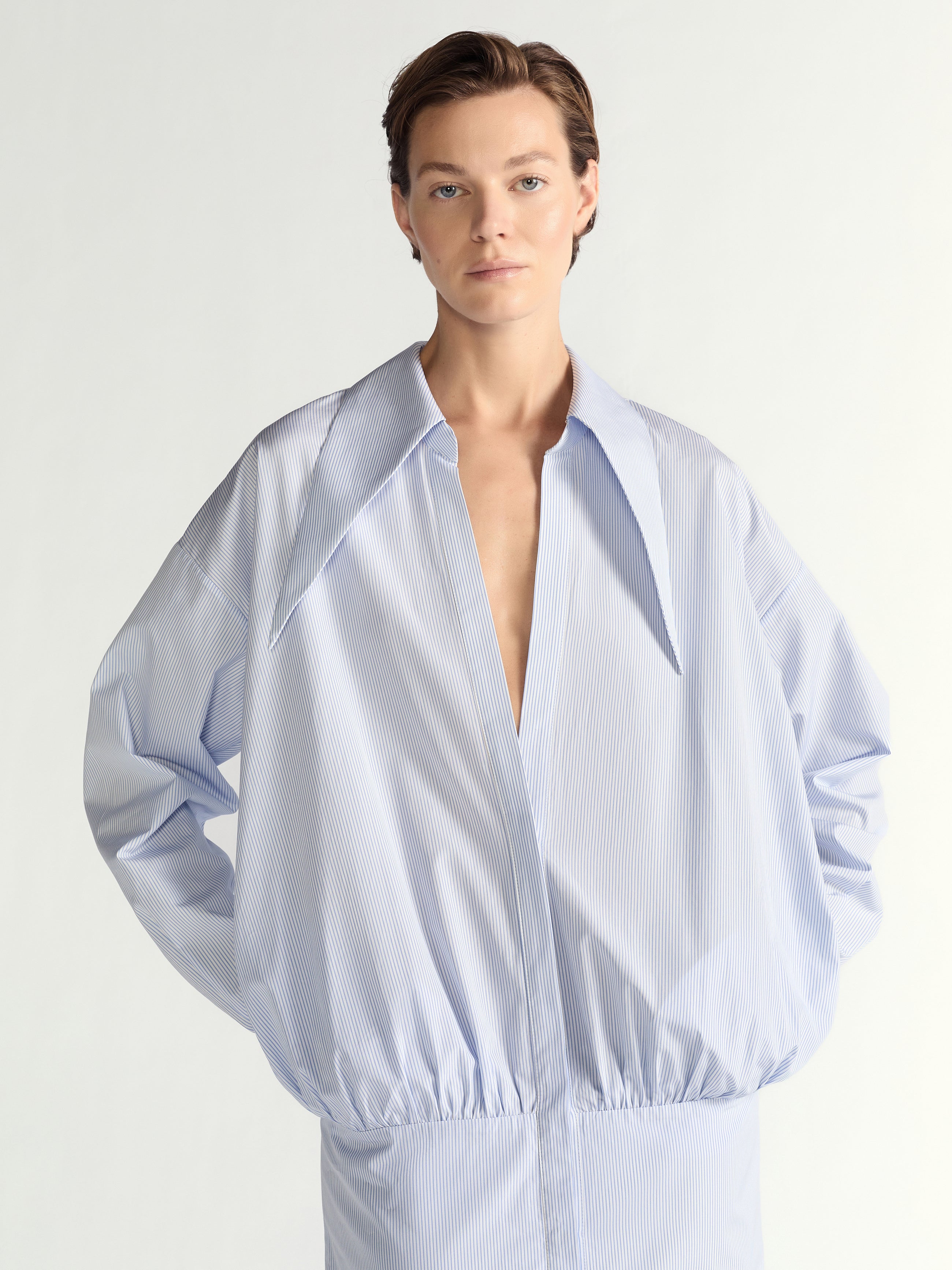 Person wearing a light blue dress against a white background