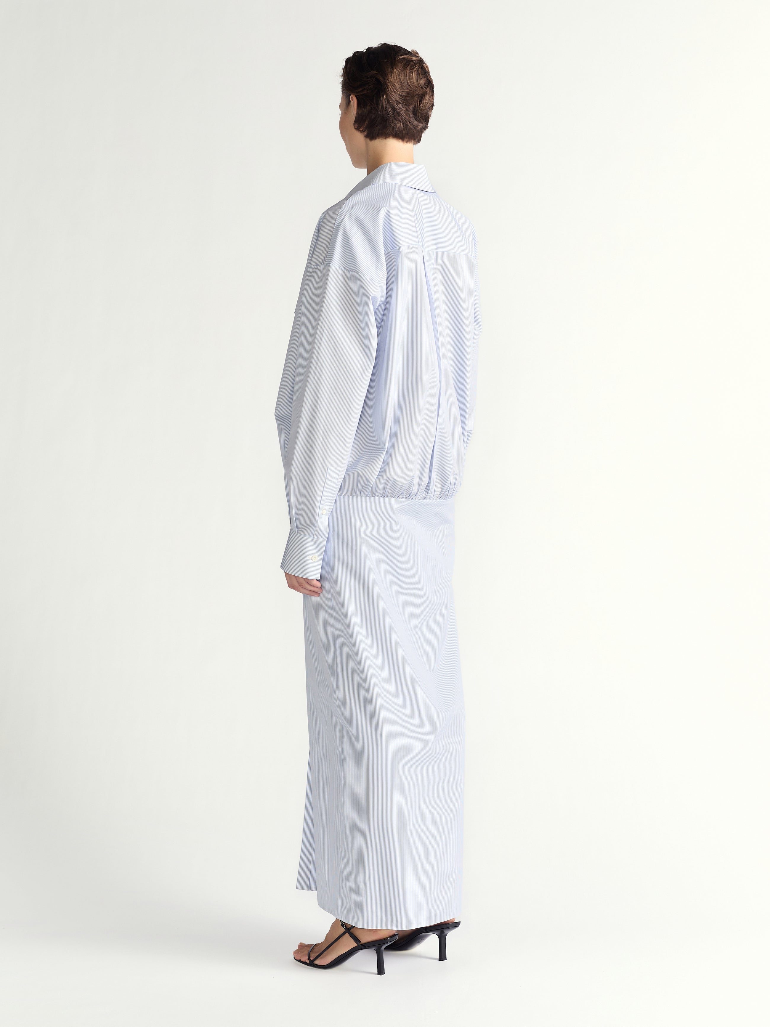Person wearing a light blue stripe ddress on a white background