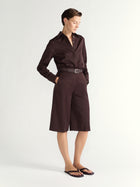 Woman wearing a brown shirt and brown shorts on a white background