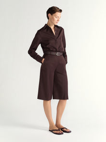 Woman wearing a brown shirt and brown shorts on a white background