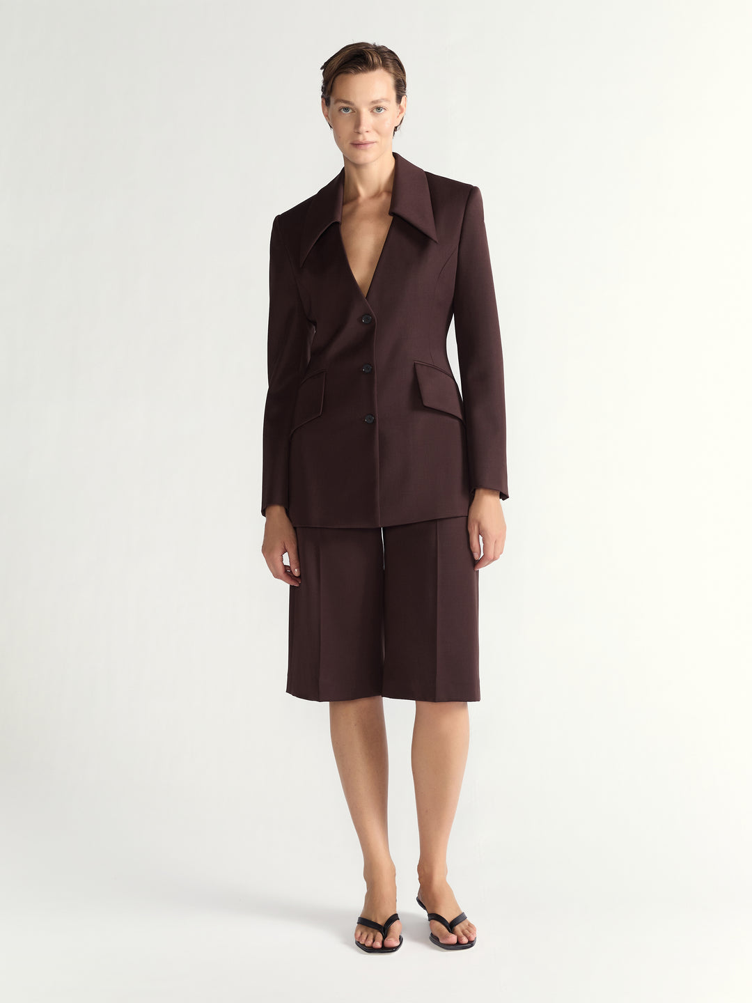 Woman wearing a brown suit with a jacket and shorts on a white background