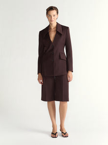 Woman wearing a brown suit with a jacket and shorts on a white background