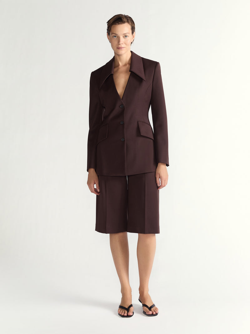 Woman wearing a brown suit with a jacket and shorts on a white background