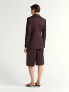 Woman wearing a brown suit with a blazer and pants on a white background