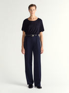 Person wearing a black top and navy pants on a white background