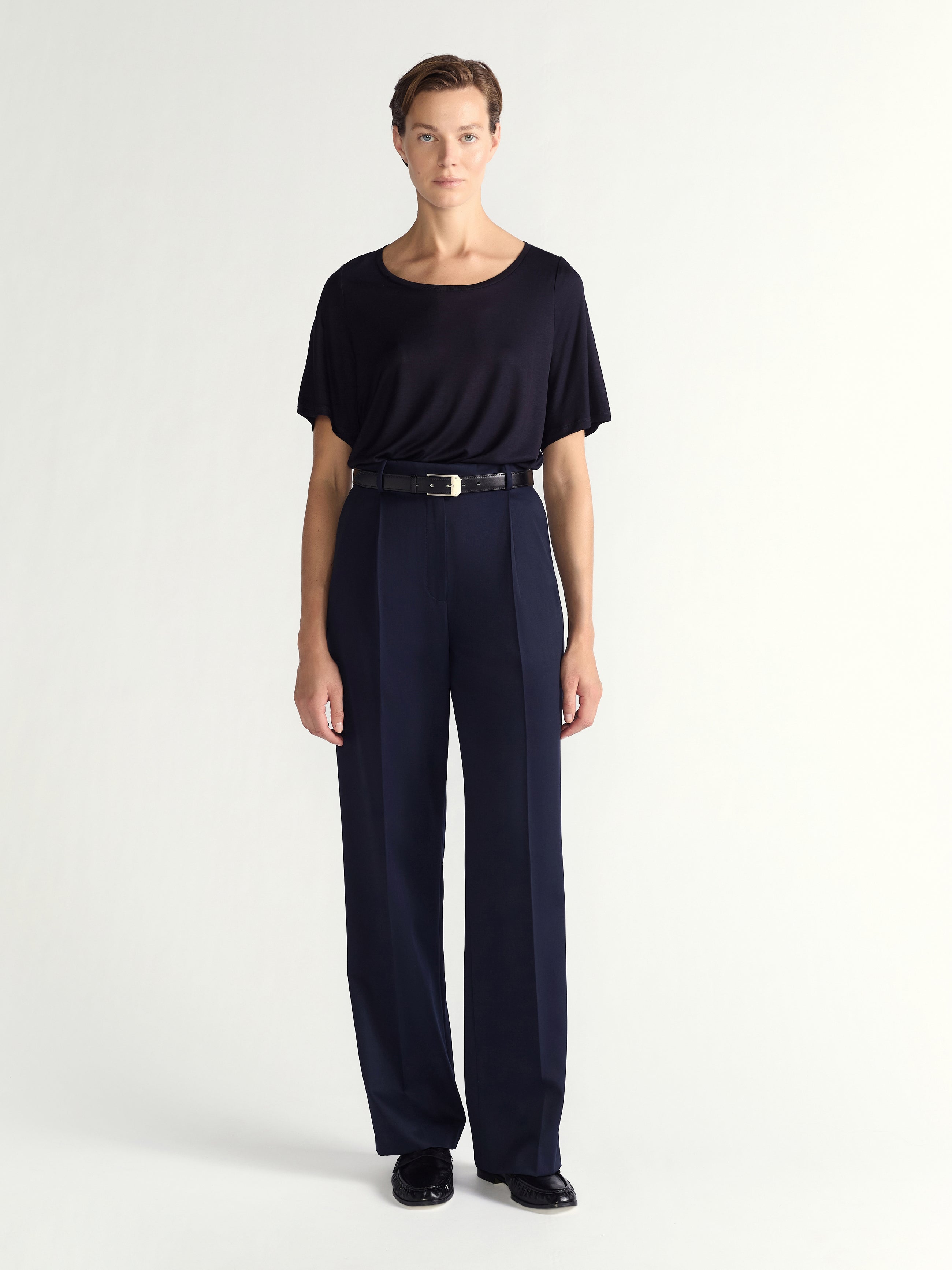 Person wearing a black top and navy pants on a white background