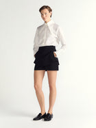 Person wearing a white shirt and black skort on a white background