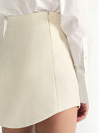 Beige skirt worn with a white shirt on a plain background