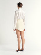 Person wearing a white blouse and cream skirt on a plain background