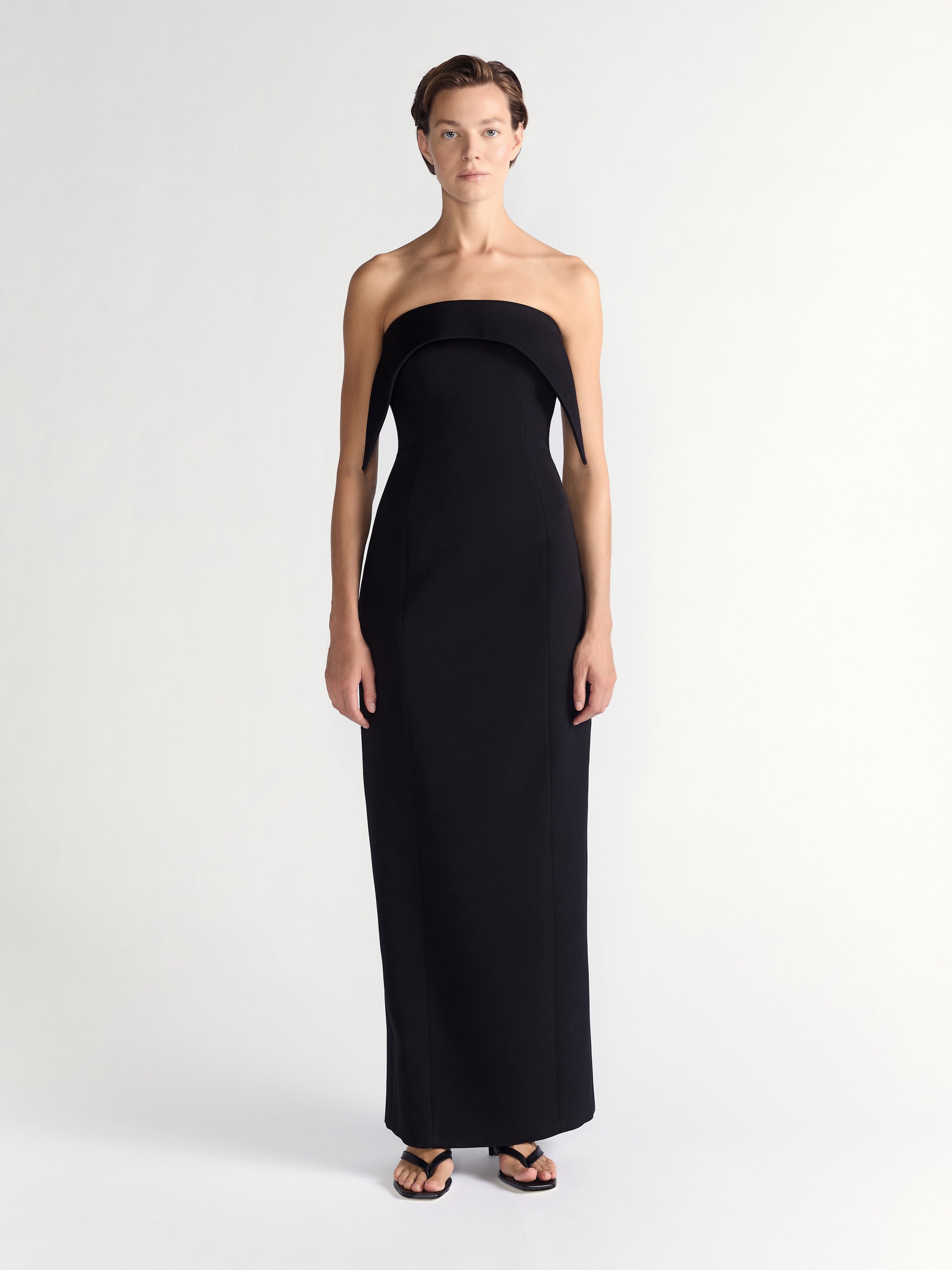 Woman wearing a black strapless gown on a white background